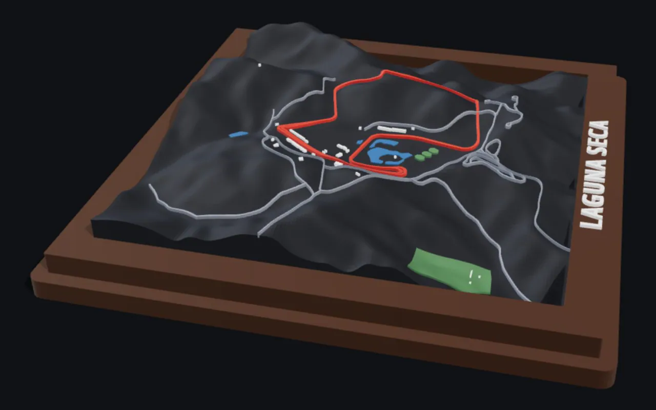 BambiMaps relief of Laguna Seca raceway: the circuit raised in red over dark hilly terrain in a stepped walnut frame